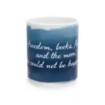 The Inspirational Ceramic Mug features a blue background with white cursive text: freedom, books, flowers & moon. Perfect gift for book lovers, coffee enthusiasts, or home decor.