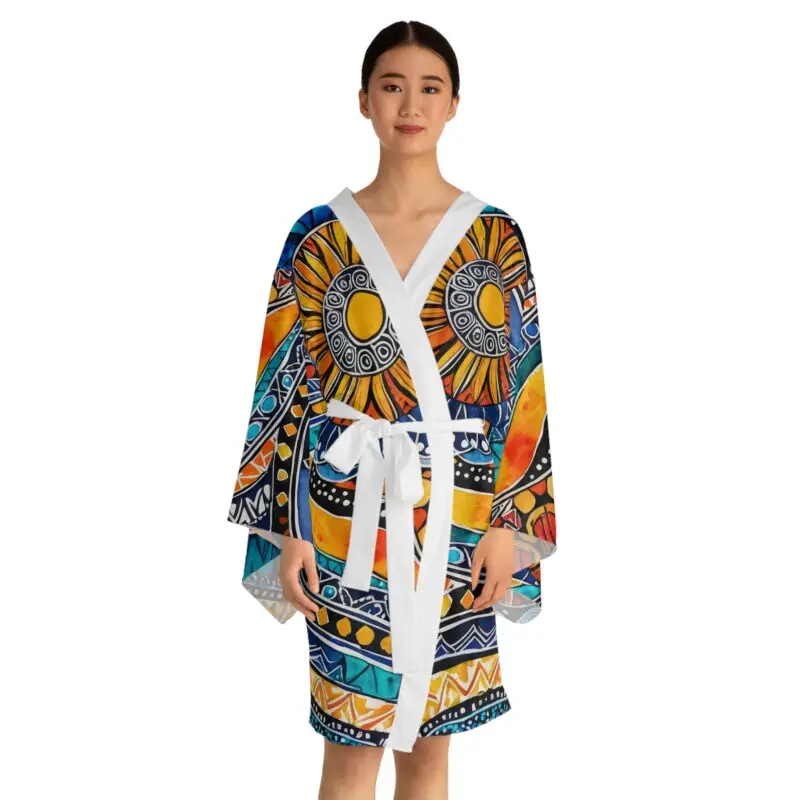 A woman faces forward wearing the Vibrant Long Sleeve Kimono Robe—a boho chic cover-up with abstract sun and geometric designs in orange, yellow, blue, and black—tied at the waist with a white belt.